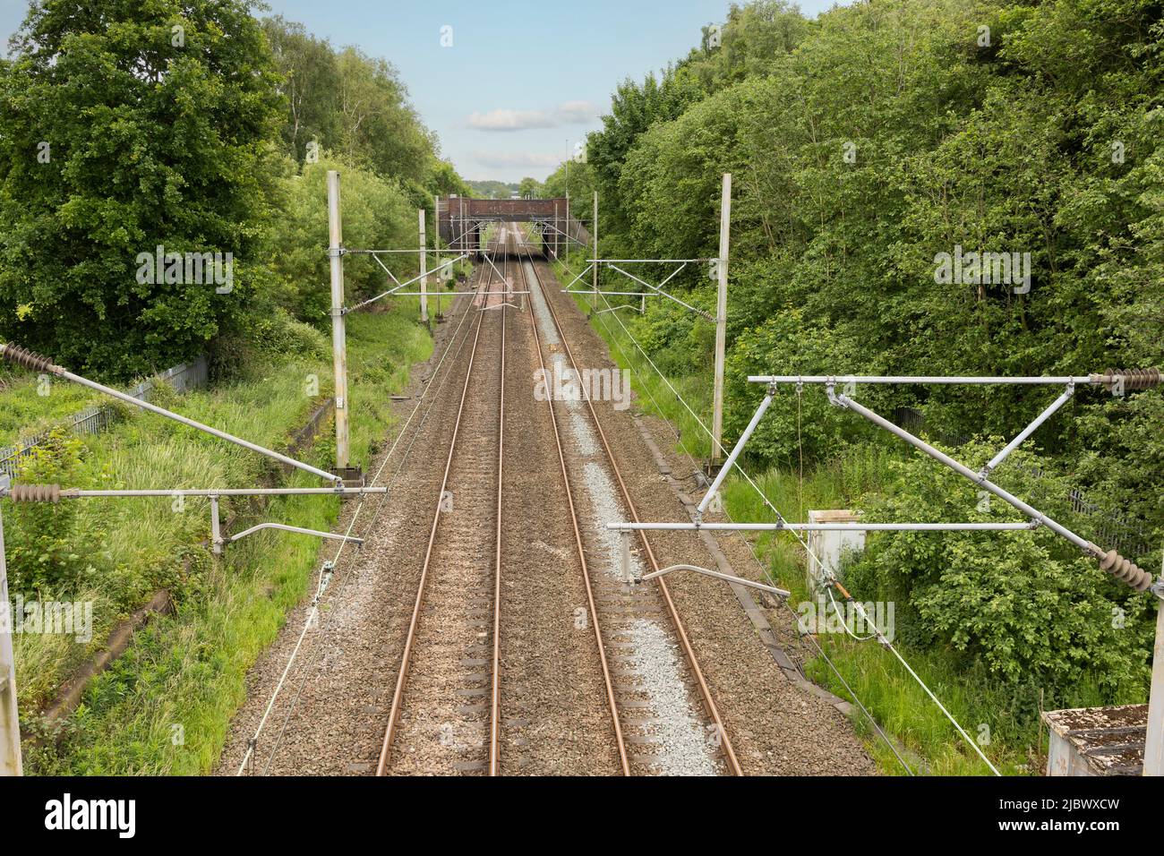 Die Gleise fahren bis zur Entfernung, auf der die von oben aufgenommenen Oberleitungsanlagen angezeigt werden Stockfoto