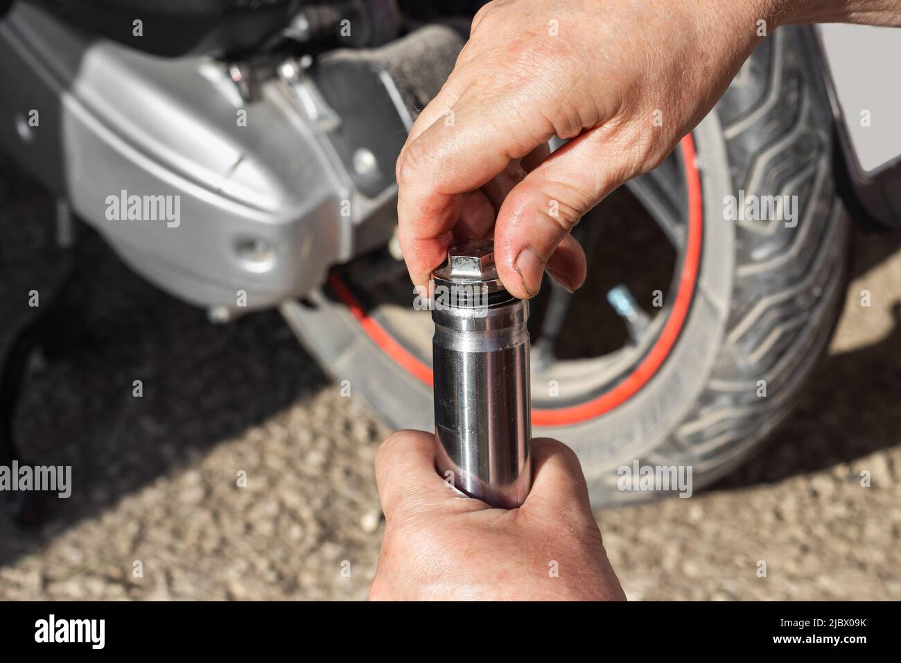 Ölwechsel, Wartung und Reparatur von Motorrädern. Ein Automechaniker schraubt den Stopfen am Stoßdämpfer der Vorderradgabel eines Motorrads ab. Stockfoto