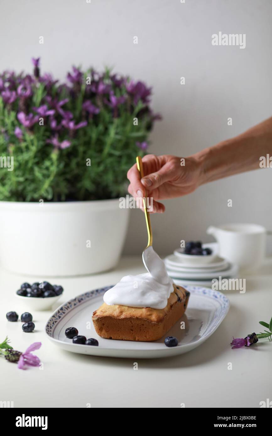 Frau, die den gebumpften Kuchen mit Glasur dekoriert, Nahaufnahme der Hand, die den Kuchen schmückt. Stockfoto