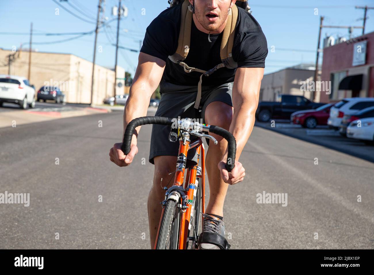 Nahaufnahme eines jungen Mannes, der mit einem einzigen Schnellfahrrad in einer städtischen Umgebung arbeitet Stockfoto