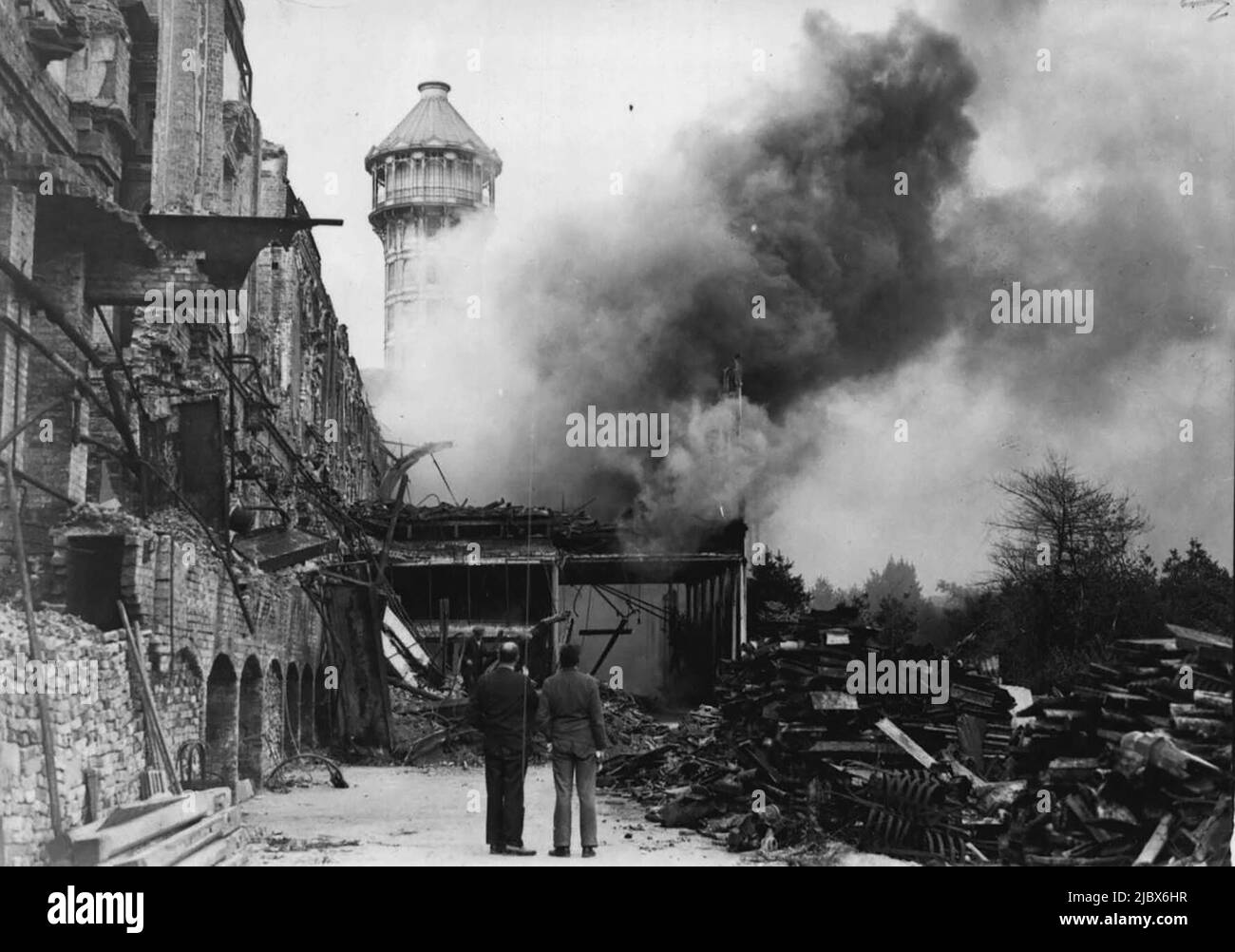 Ein weiteres Feuer bricht in den Ruinen des Crystal Palace aus - Feuerwehrmänner bei der Arbeit am Gebäude der brennenden Kunstschule. Das Dach fiel ein und das Gebäude wurde entklatzt. In den Ruinen des Crystal Palace, der berühmten Glasausstellungshalle auf dem Sydenham Hill, brach ein weiteres Feuer aus. Hier, die im letzten Winter durch den Brand des Jahrhunderts zerstört wurde. Heute Nachmittag wurde das ehemalige Kunstschulgebäude und die Eislaufbahn, vor den Flammen gerettet, verbrannt. 19. August 1937. (Foto von Associated Press Photo). Stockfoto