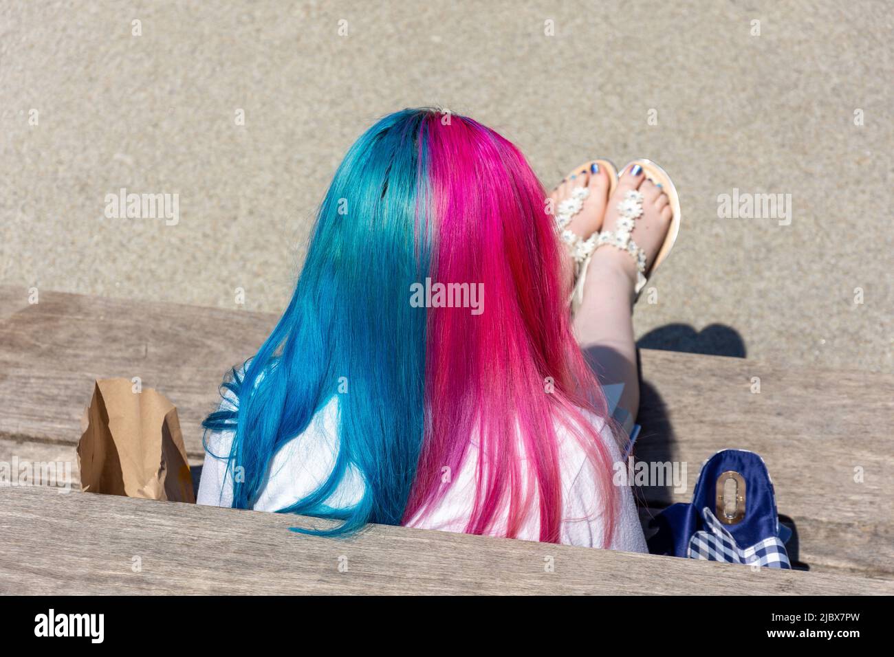 Junge Frau mit gefärbten Haaren sitzt im Oracle Riverside Einkaufszentrum, Reading, Bukshire, England, Vereinigtes Königreich Stockfoto