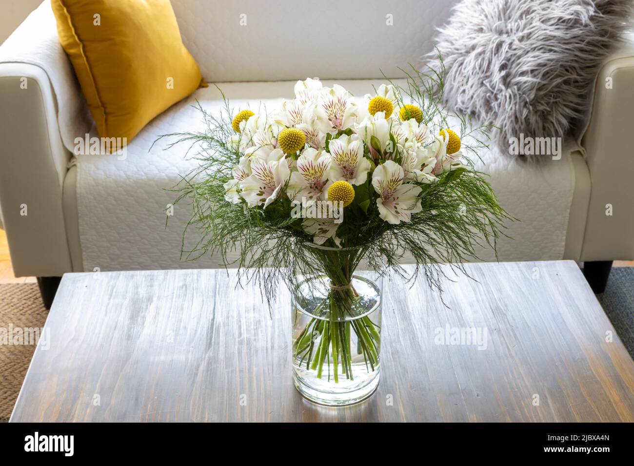 Craspedia und Alstroemeria Blumen in einer Vase auf einem Couchtisch Stockfoto
