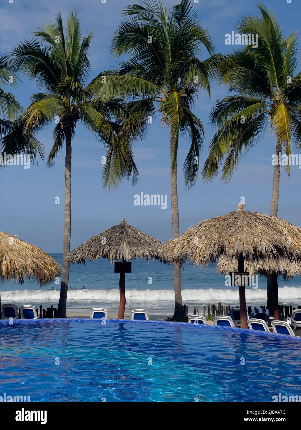 Strandhotel mit Swimmingpool und Palapas am La Playa Ropa in Zihuatanejo, Mexiko Stockfoto