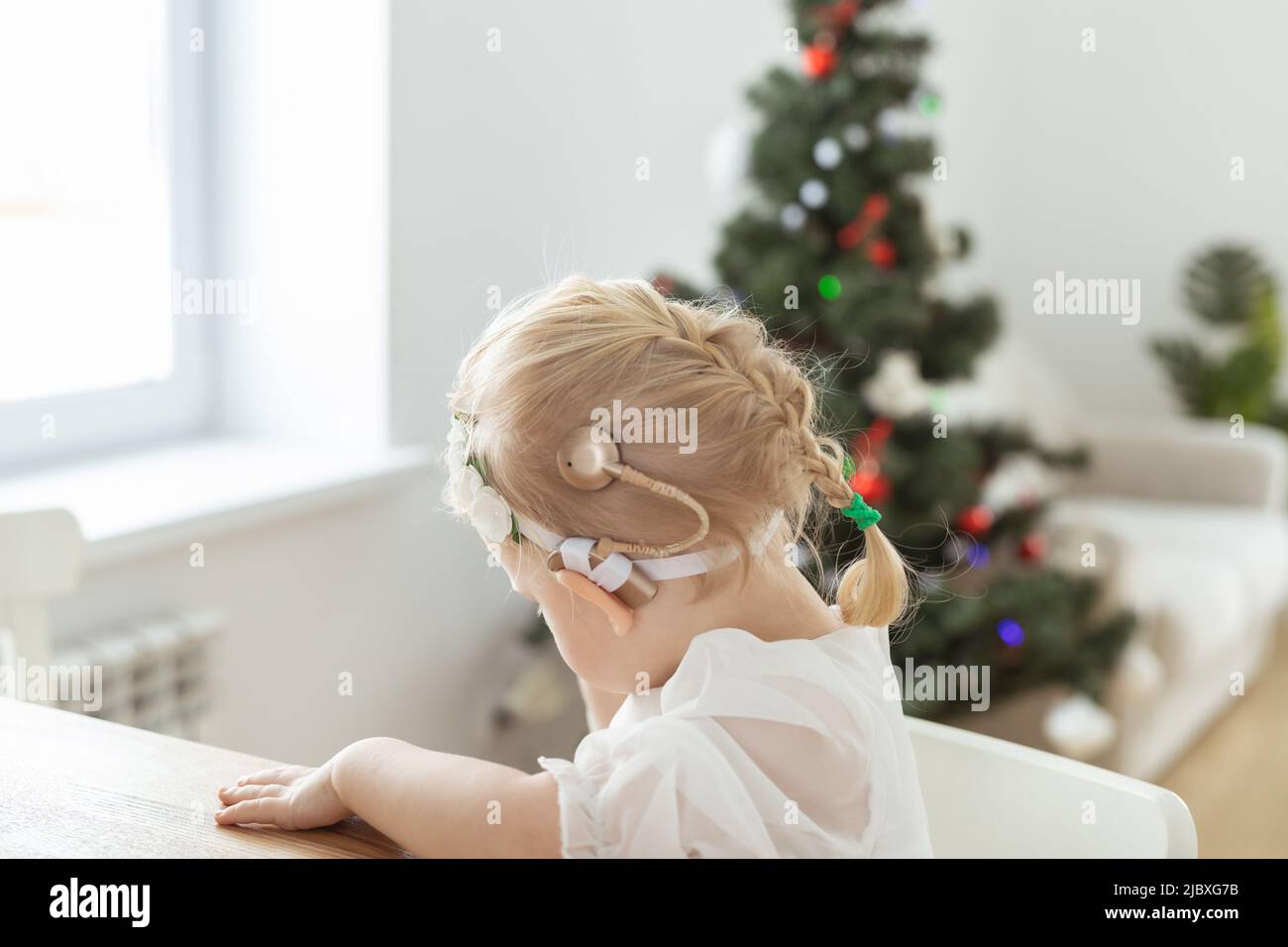 Kindermädchen in weihnachtskleid mit Cochlea-Implantaten gekleidet Spaß zu Hause - Vielfalt und Hörgeräte und innovative Technologien für die Behandlung Stockfoto