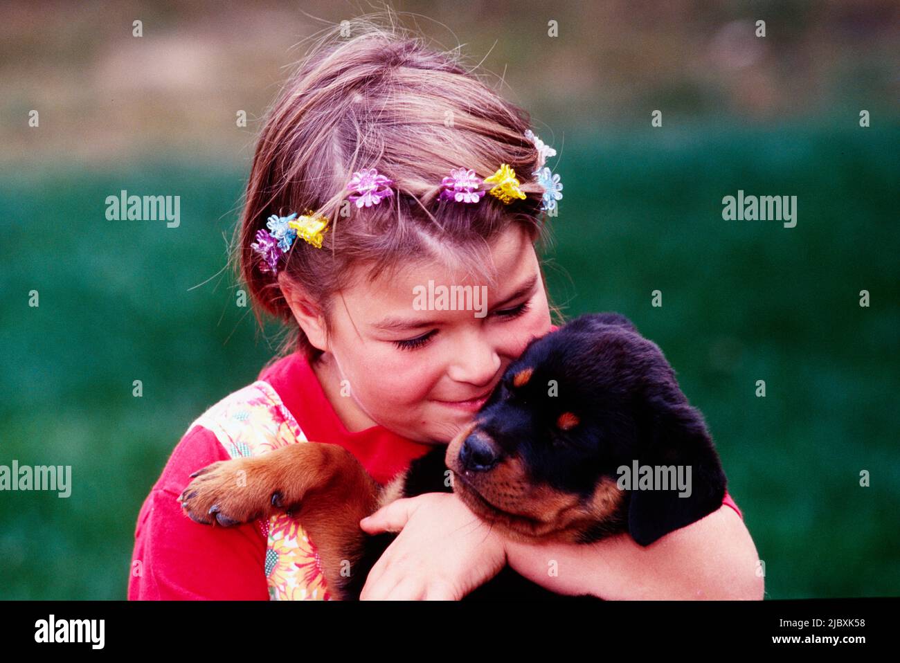 Ein junges Mädchen, das mit einem rottweiler Welpen kuschelt Stockfoto