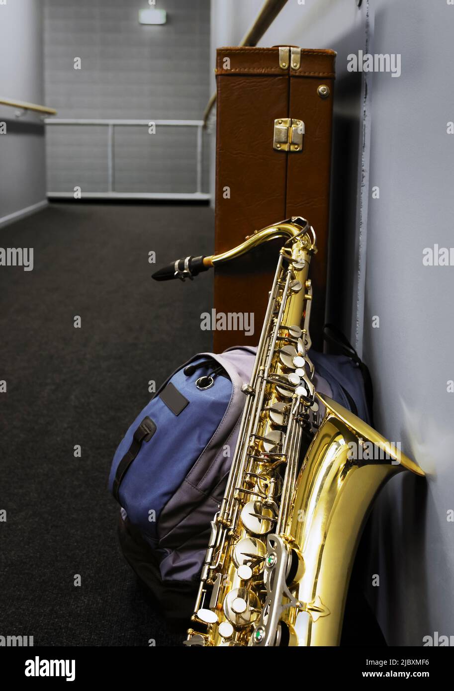 Saxophon lehnt sich im Schulkorridor an den Schulrucksack Stockfoto