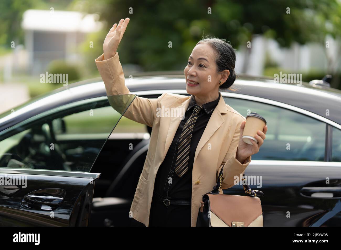 Porträt einer asiatischen Geschäftsfrau, die aus dem Luxusauto kommt, während sie ins Büro kommt. Account- und Finanzkonzept. Stockfoto
