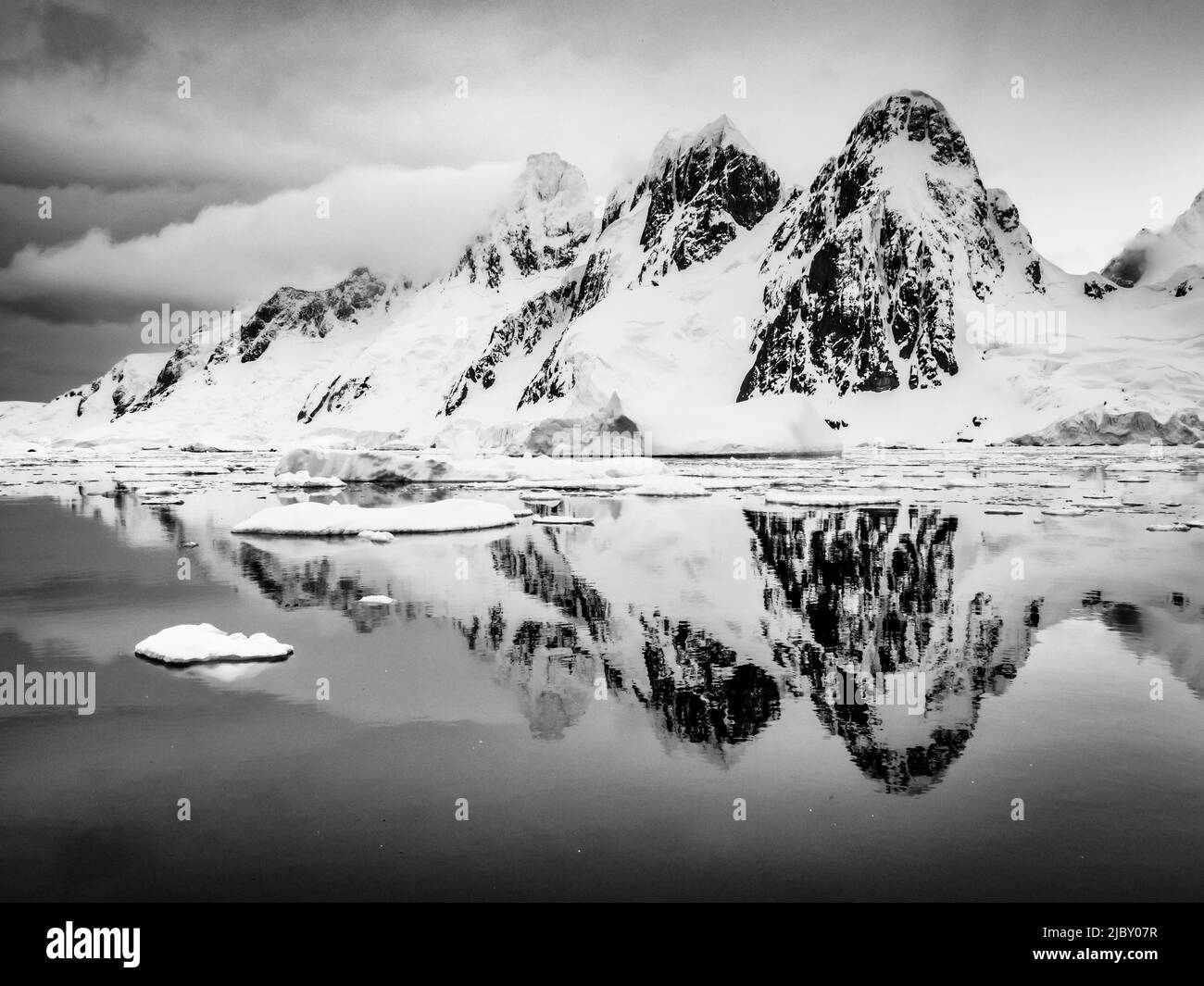Black & White, Packeis bildet reflektierende Pools für die bergige Küste von Booth Island, Antarktis Stockfoto
