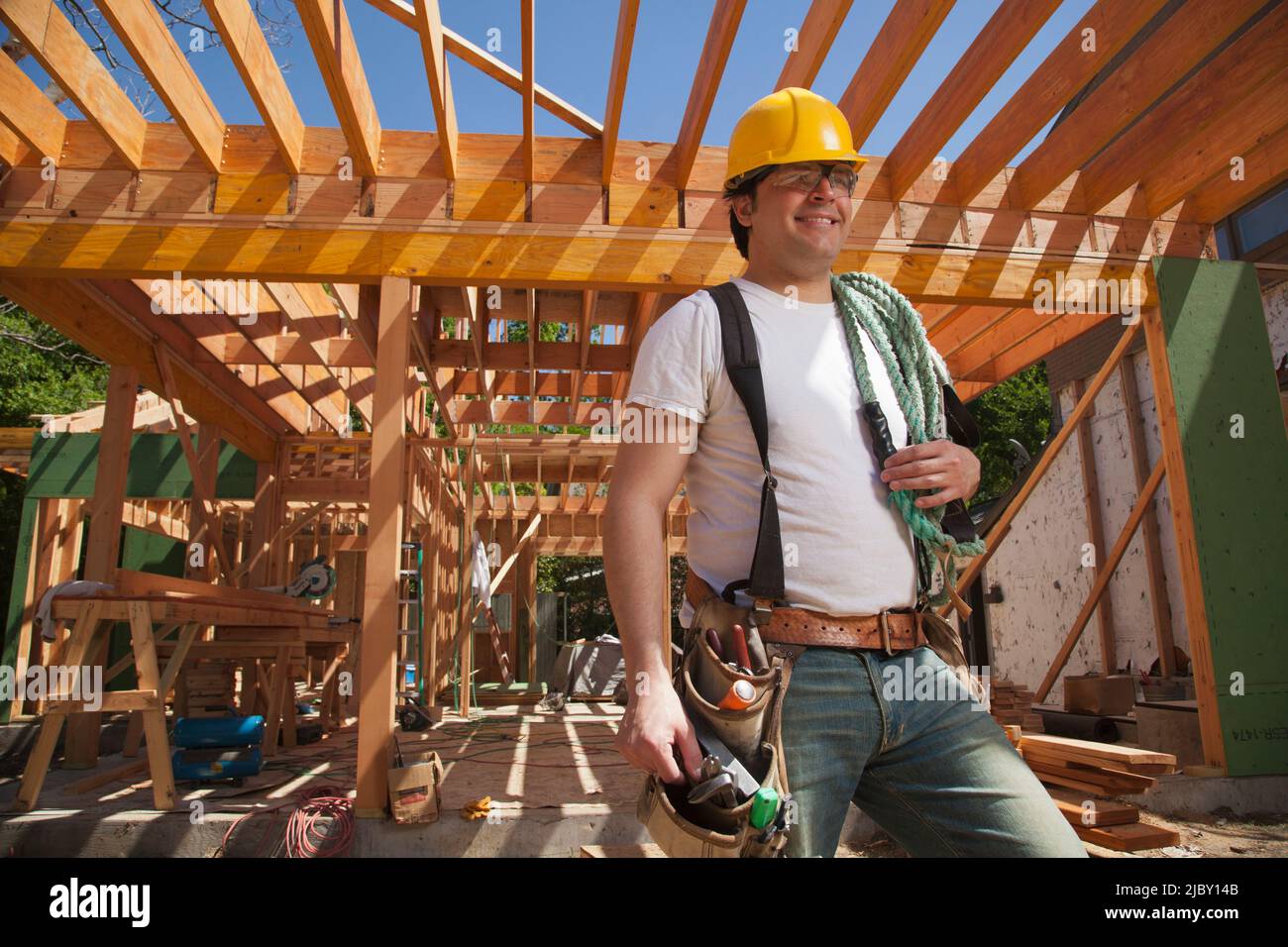 Porträt eines Bauarbeiters, der einen Hut und einen Werkzeuggürtel trägt, während er auf der Baustelle steht Stockfoto