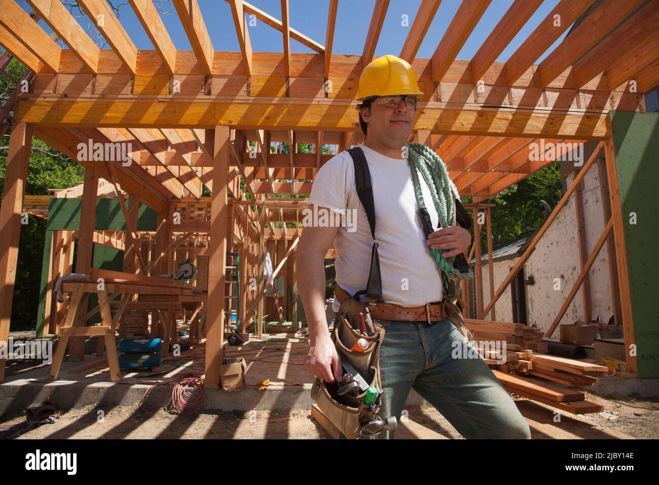 Porträt eines Bauarbeiters, der einen Hut und einen Werkzeuggürtel trägt, während er auf der Baustelle steht Stockfoto
