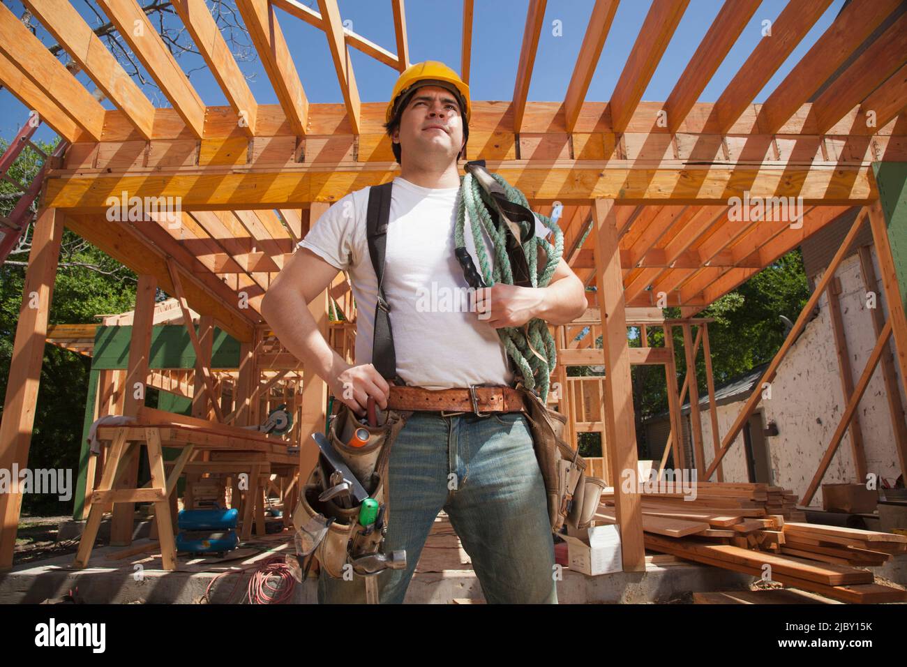 Porträt eines Bauarbeiters, der einen Hut und einen Werkzeuggürtel trägt, während er auf der Baustelle steht Stockfoto