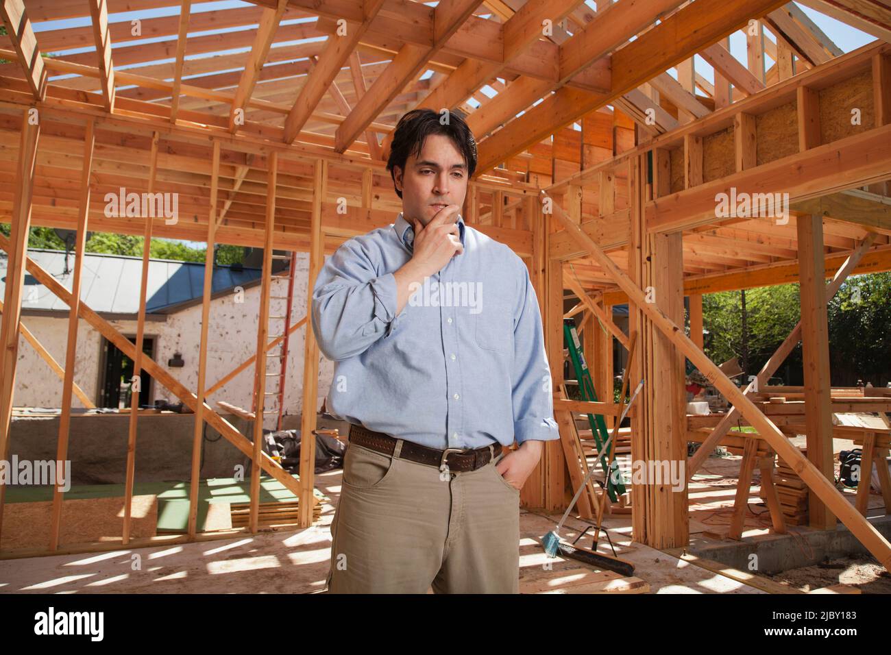 Mann mit der Hand auf dem Kinn in tiefem Denken, während er auf der Baustelle stand Stockfoto