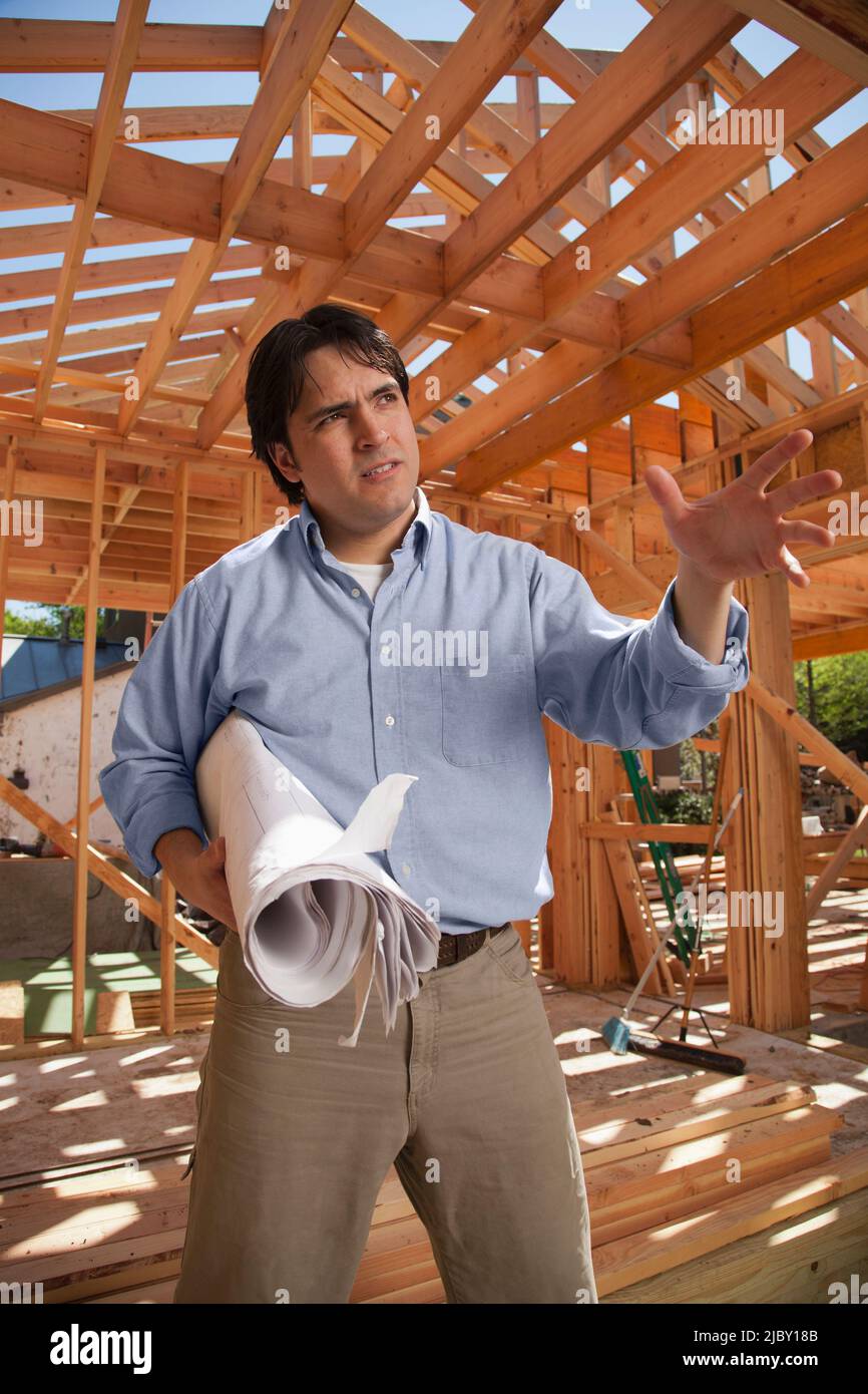 Auftragnehmer, der Pläne auf der Wohnbaustelle hält Stockfoto