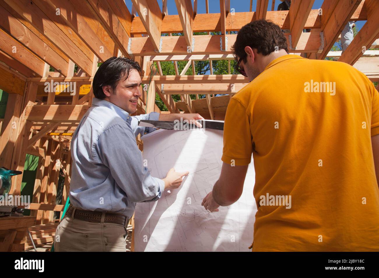 Auftragnehmer übergeht Pläne mit einem Mann auf einer Wohnbaustelle Stockfoto