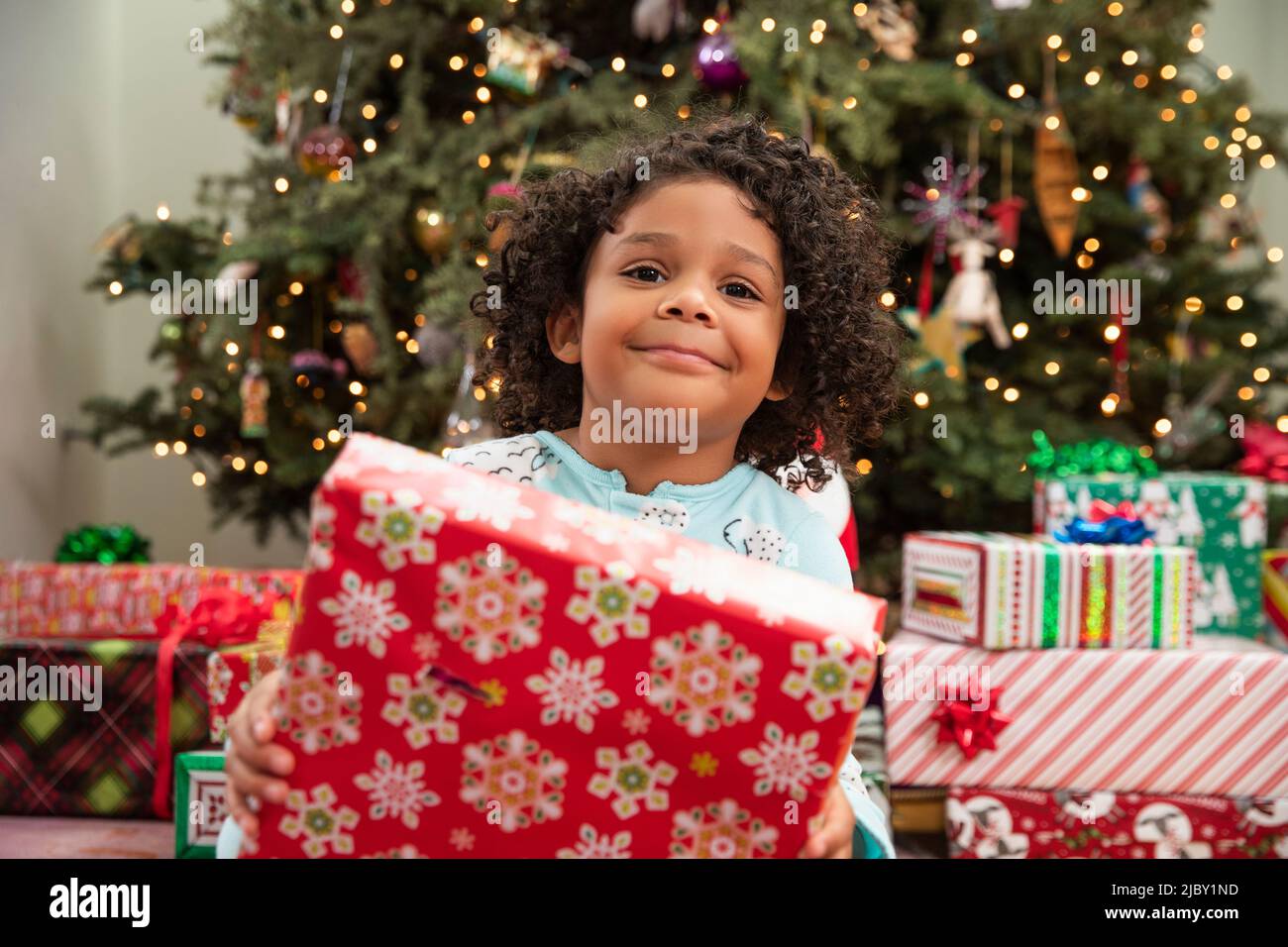 Happy girl Eröffnung ihr Weihnachtsgeschenk mit großen glücklichen Lächeln. Stockfoto