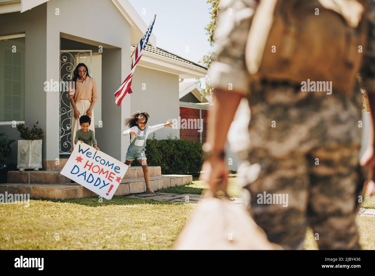 Aufgeregt junge Kinder laufen, um ihren Vater nach seiner Rückkehr aus der Armee willkommen zu heißen. Nach dem Dienst vereint sich der amerikanische Soldat wieder mit seiner Frau und seinen Kindern Stockfoto