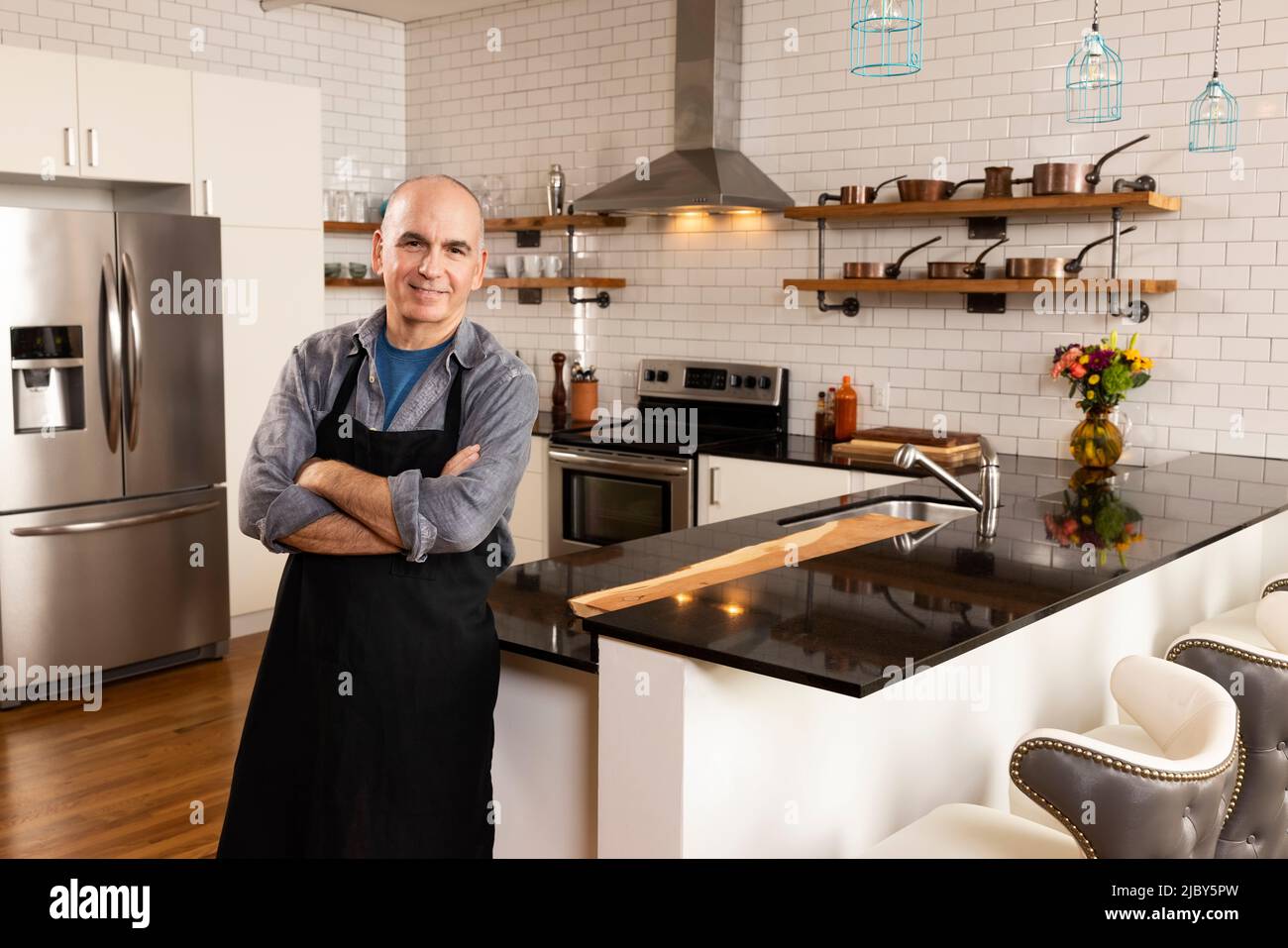 Porträt eines Mannes, der in der Küche steht und selbstbewusst in die Kamera schaut. Stockfoto