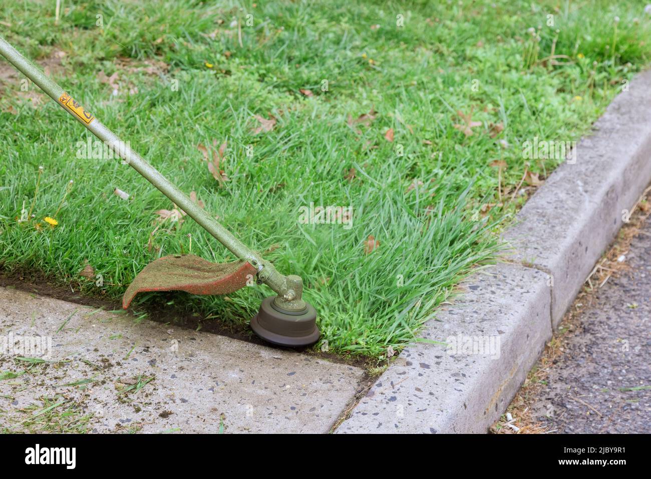 Arbeiter schneidet das Gras mit einem Fadenschneider auf Benzin Stockfoto