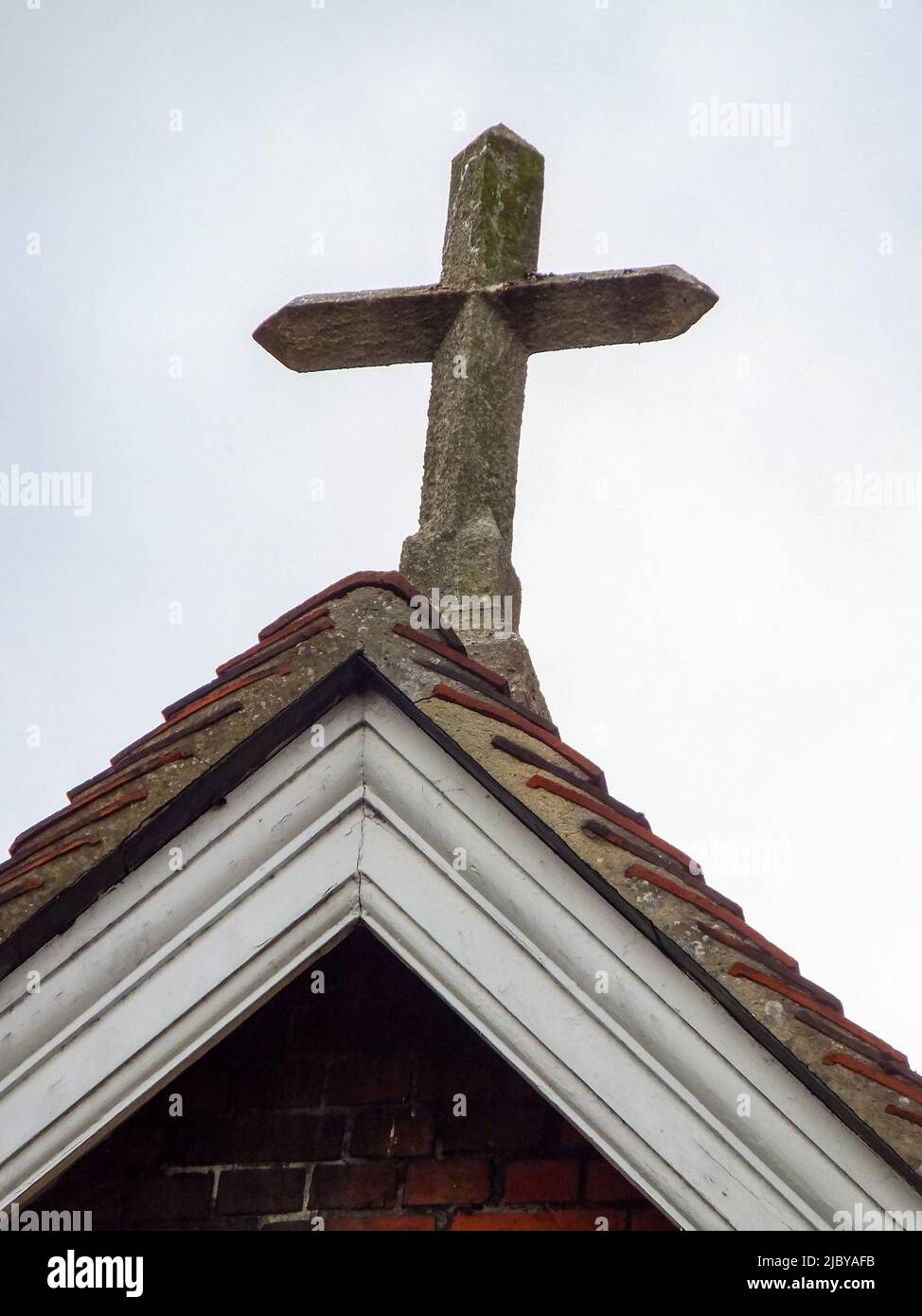 Ein Steinkreuz schmückt das Dach einer Kirche in Winchester, Hampshire, England, Großbritannien. Stockfoto
