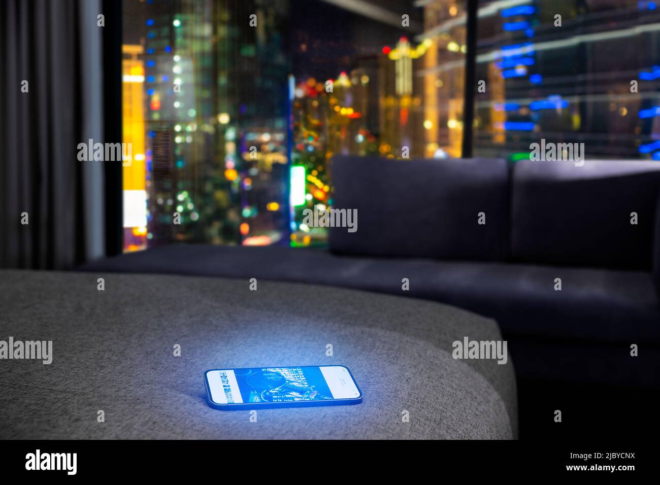 Ein Handy auf einem Bett in einem Hotelzimmer in der Nacht Stockfoto