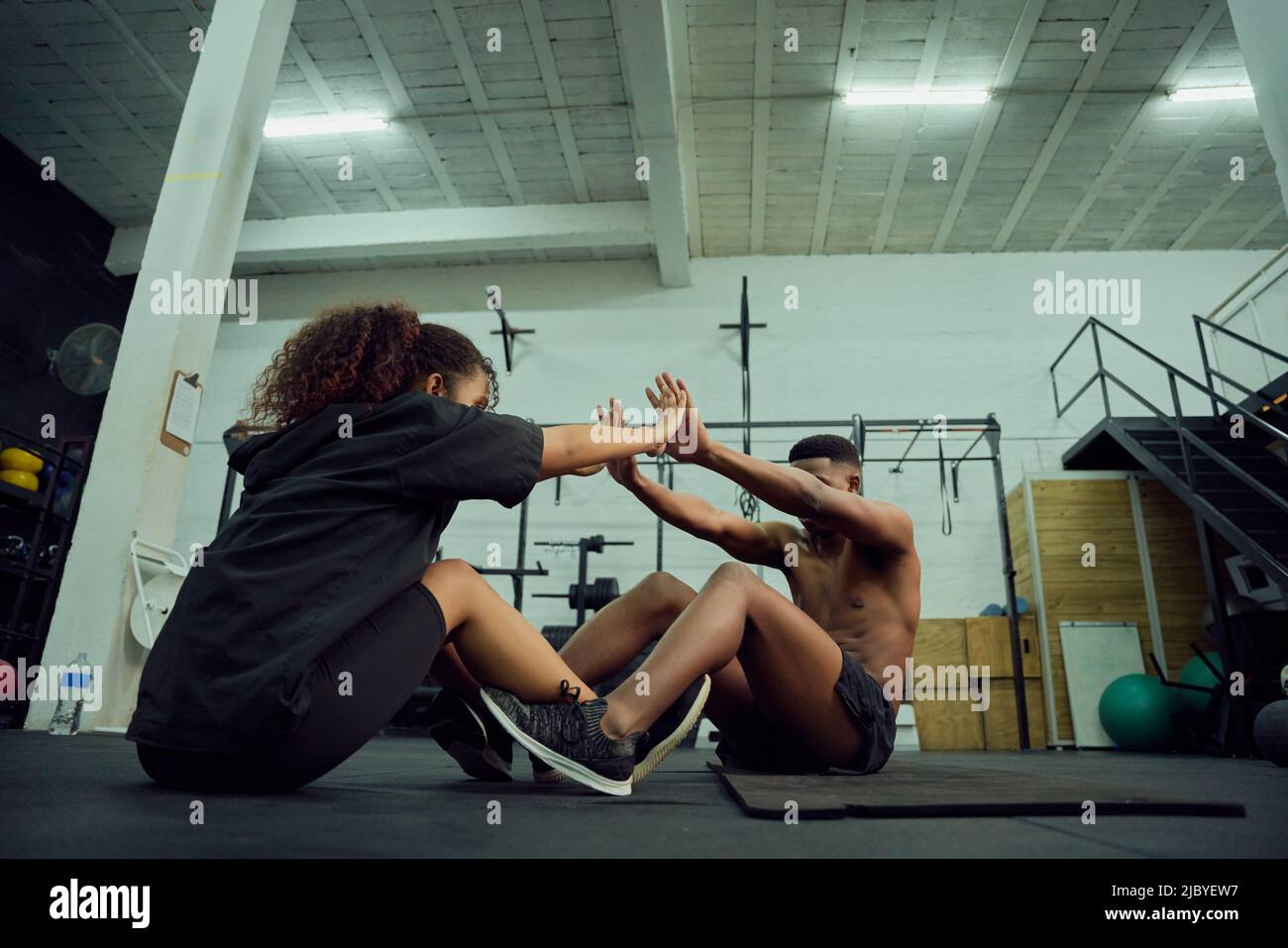 Mixed-Race-Freunde, die im Fitnessstudio Cross-Fit machen. Männlicher Personal Trainer, der afroamerikanischen Frauen nach dem Training einen High-Five gab. Hochwertige Fotos Stockfoto