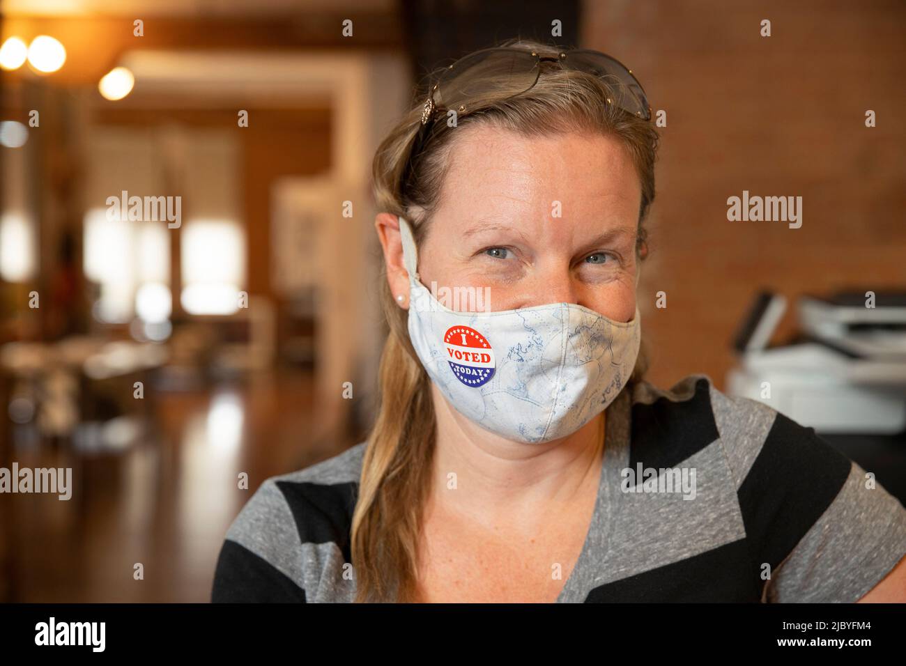 Kaukasische Frau trägt eine Maske und einen I Voted Today Aufkleber auf der Maske Stockfoto