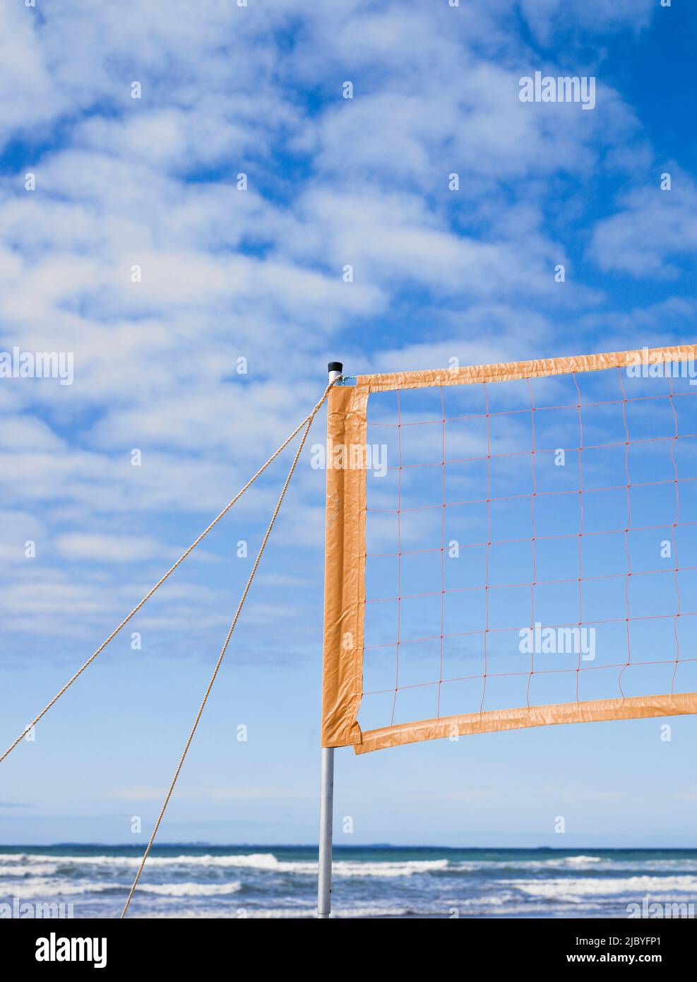 Beachvolleyballnetz aufgebaut und Wellen und blauer Himmel im Hintergrund Stockfoto