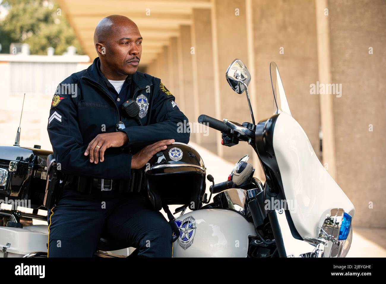 Porträt eines Polizisten, der draußen auf seinem Motorrad sitzt und lächelnd auf die Kamera blickt Stockfoto
