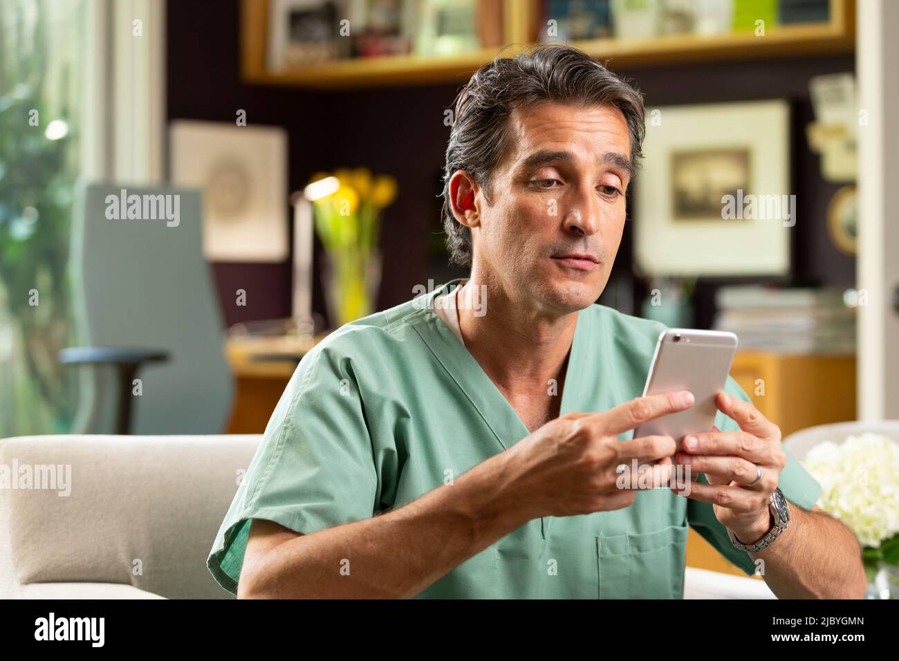 Hispanischer Arzt mit Telemedizin aus seinem Heimbüro, der per Videoanruf mit dem Patienten auf dem Handy spricht Stockfoto