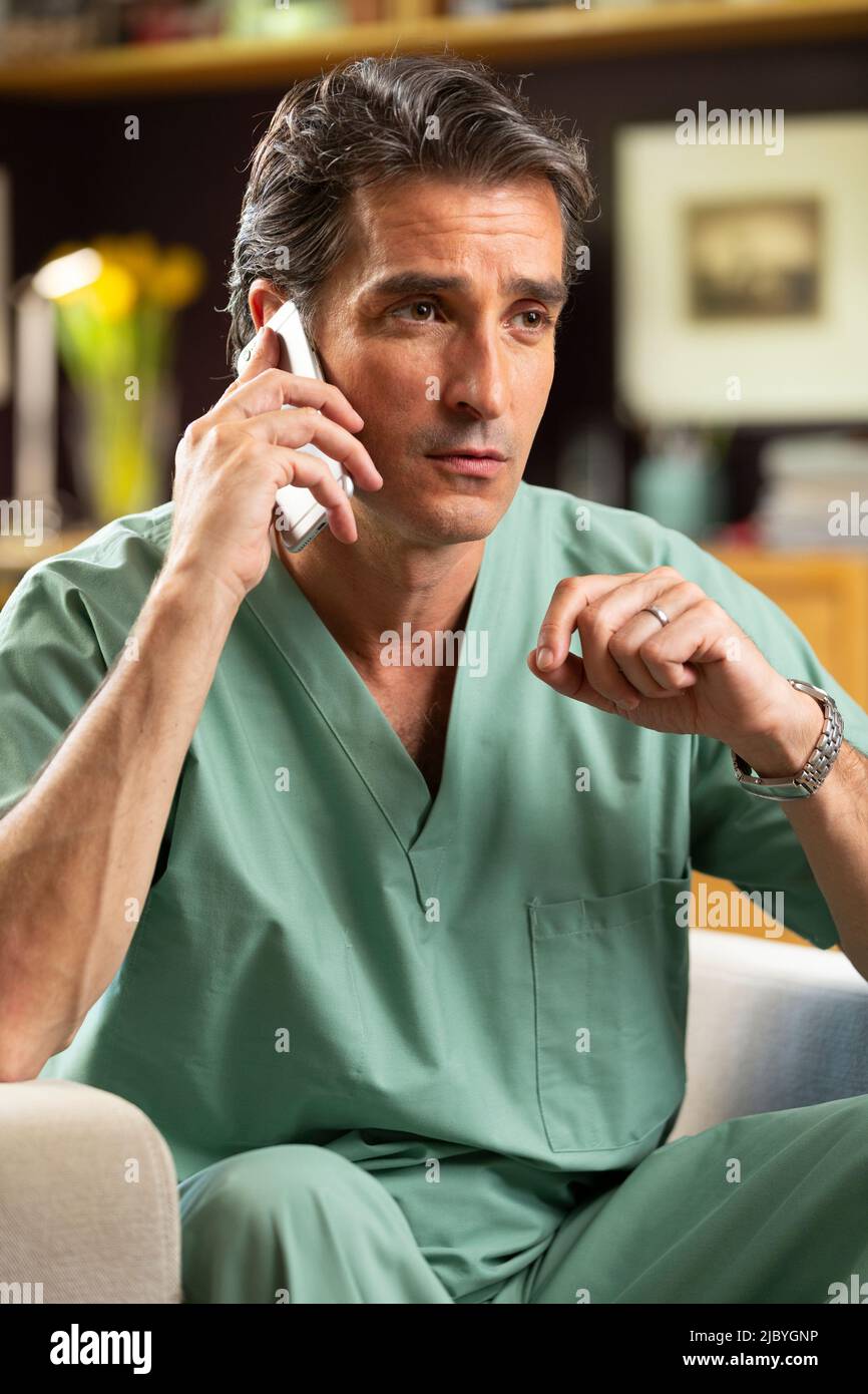 Hispanischer Arzt, der in seinem Büro Telemedizin praktiziert und mit dem Patienten am Handy spricht Stockfoto