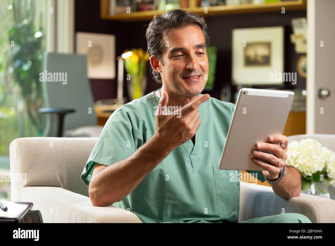 Hispanischer Arzt mit Telemedizin aus seinem Heimbüro, der per Videoanruf auf dem Tablet mit dem Patienten spricht Stockfoto