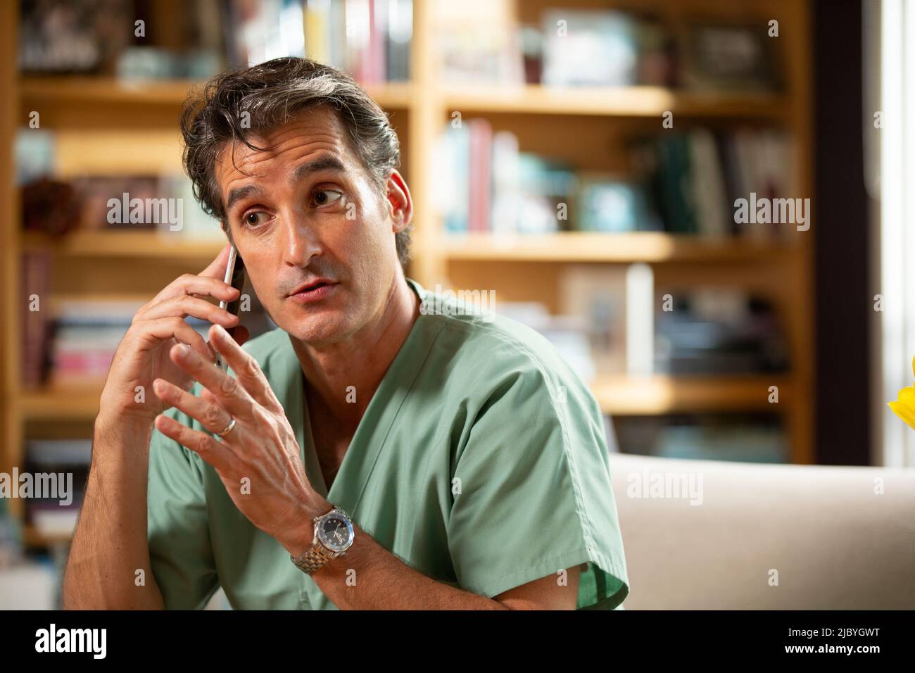 Hispanischer Arzt, der in seinem Büro Telemedizin praktiziert und mit dem Patienten am Handy spricht Stockfoto