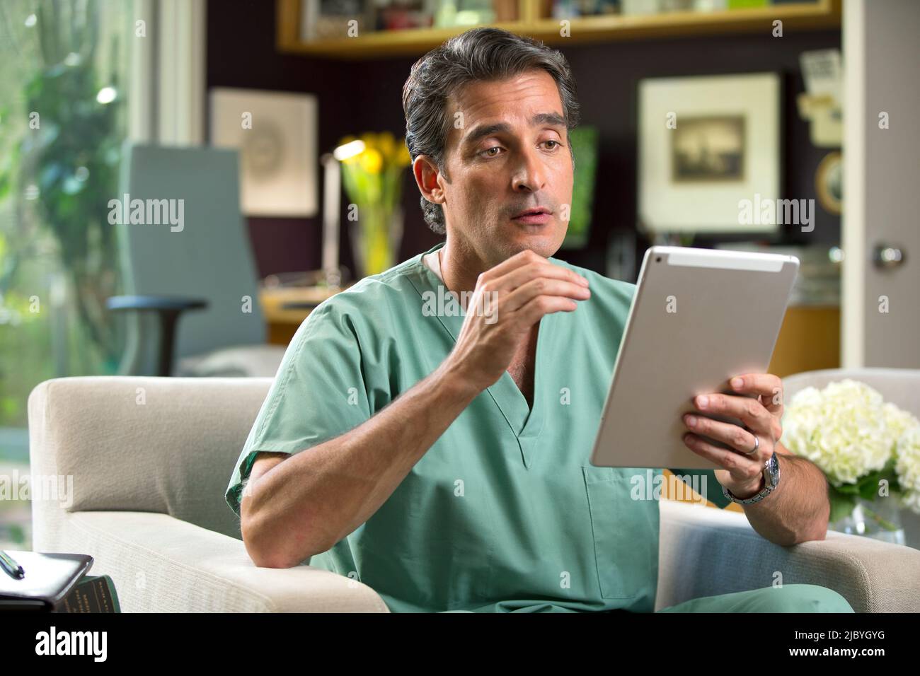 Hispanischer Arzt mit Telemedizin aus seinem Heimbüro, der per Videoanruf auf dem Tablet mit dem Patienten spricht Stockfoto