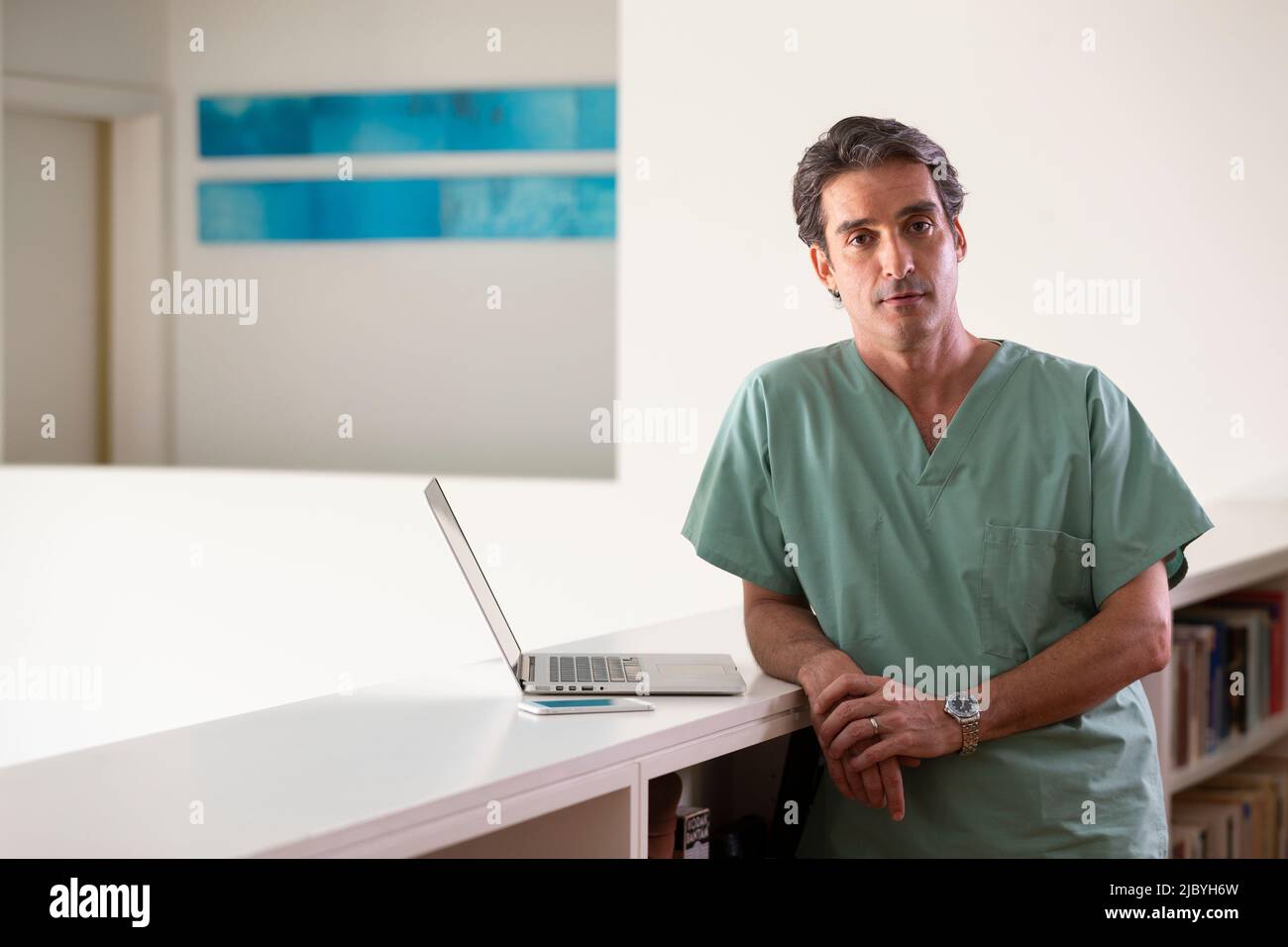Porträt eines hispanischen männlichen Arztes in seiner Wohnung, der eine Pause vom Praktizieren der Telemedizin machte Stockfoto