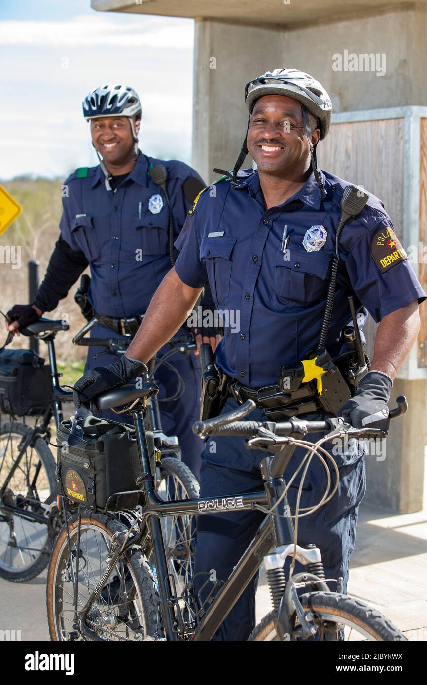 Porträt von Fahrradpolizisten, die draußen mit ihren Fahrrädern stehen und lächelnd auf die Kamera schauen Stockfoto