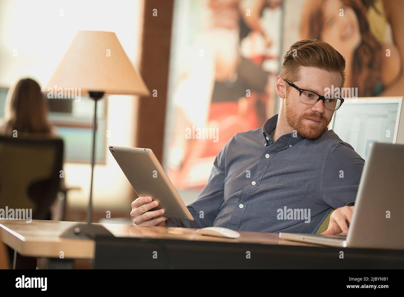 Kaukasische Geschäftsmann mit digitalen Tablet und Laptop im Büro Stockfoto