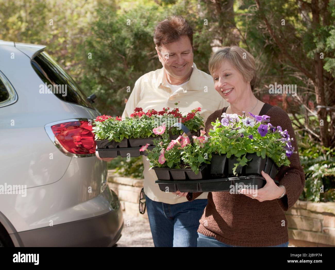 Ehemann und Ehefrau tragen Tabletts mit Blumen Stockfoto