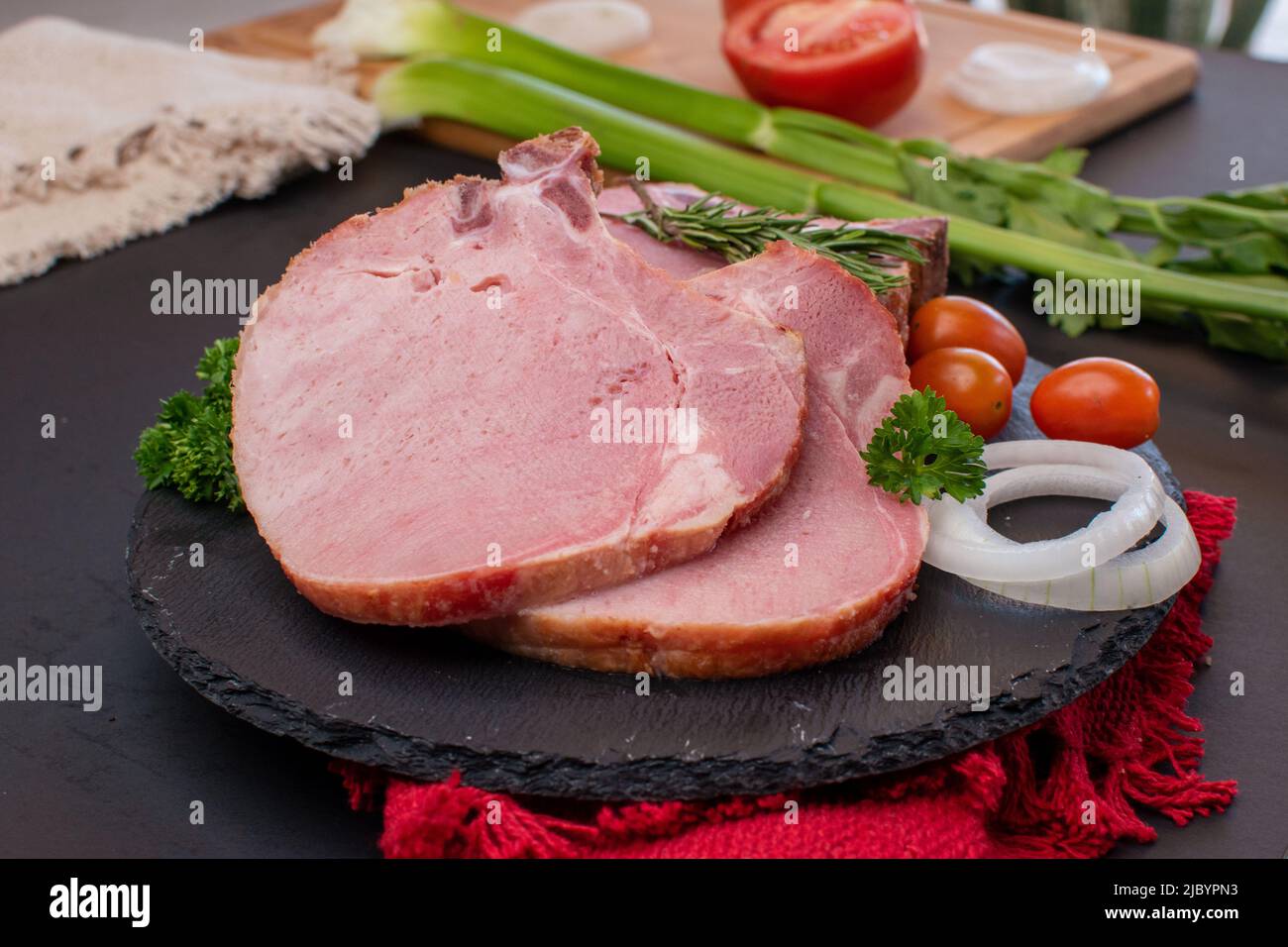 Zwei Stücke rohes Schweinekotelett mit Zwiebeln und Kirschtomaten Stockfoto