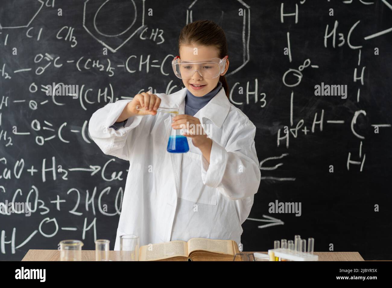 Gymnasiatin, die im Chemielabor experimentiert, Schülerin, die sich um Experimente im Chemieunterricht kümmert, verwenden Sie eine Pipette für Flüssigkeit Stockfoto