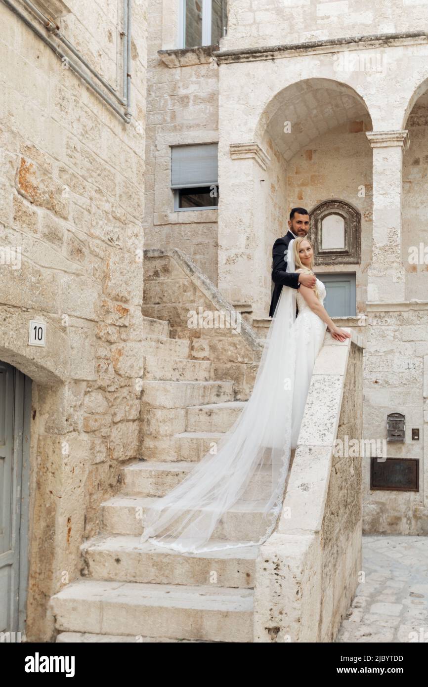 Vertikales Porträt von Bräutigam und Braut, Frau und Mann, gerade auf Steintreppen verheiratet. Blick auf die Kamera. Italien traditionell Stockfoto
