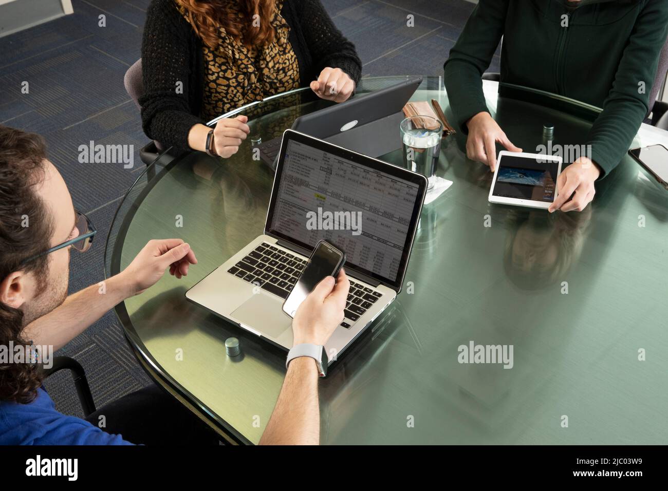 Aufnahme von drei Personen auf Laptops und Tablets während eines Meetings. Stockfoto