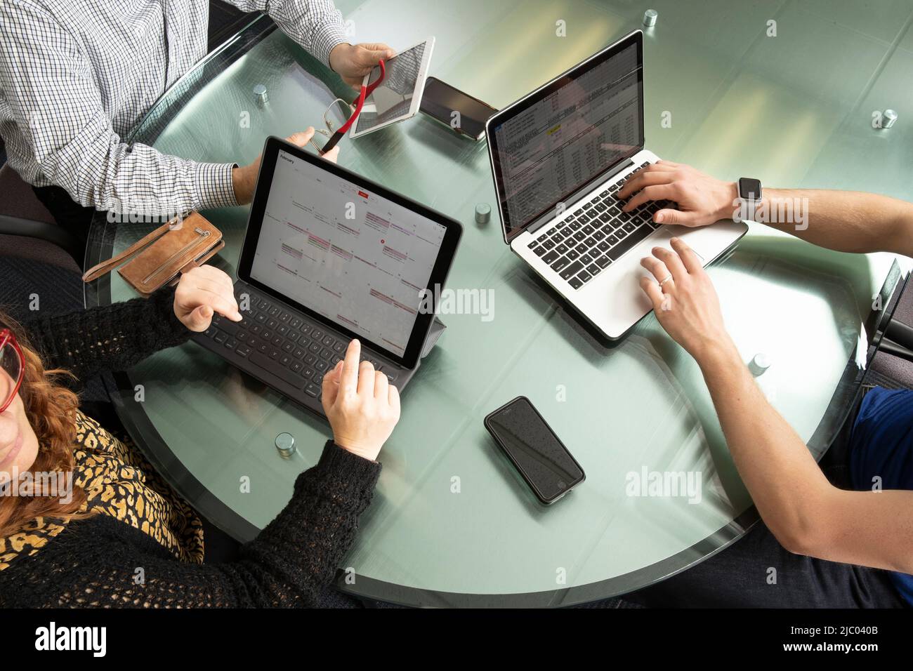 Aufnahme von drei Personen, die an Computern und Tablets arbeiten. Stockfoto