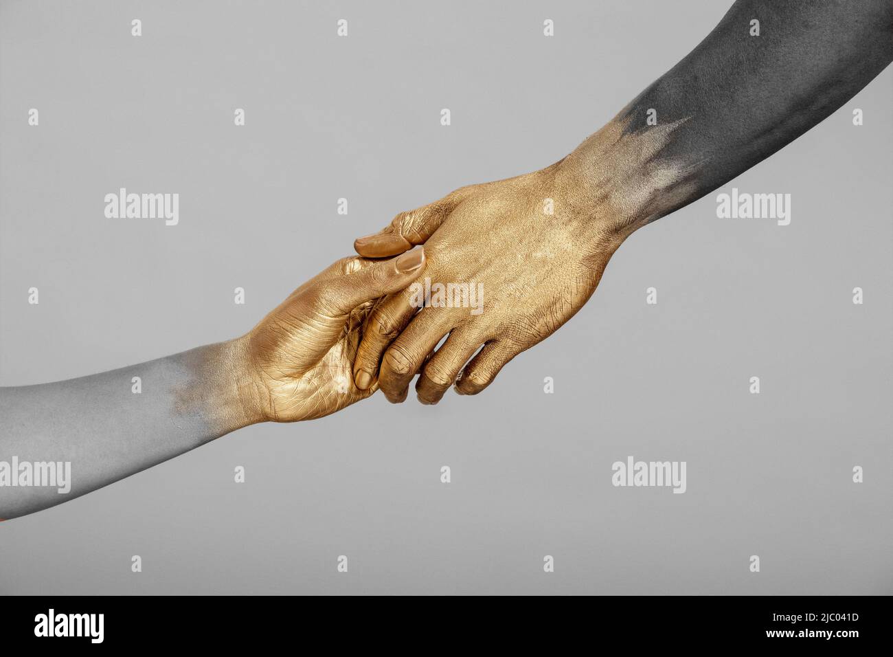 Entsättigte Aufnahme einer Frau mit gemischter Rasse und eines schwarzen Mannes mit goldfarbenen Händen, die die Hände halten. Stockfoto