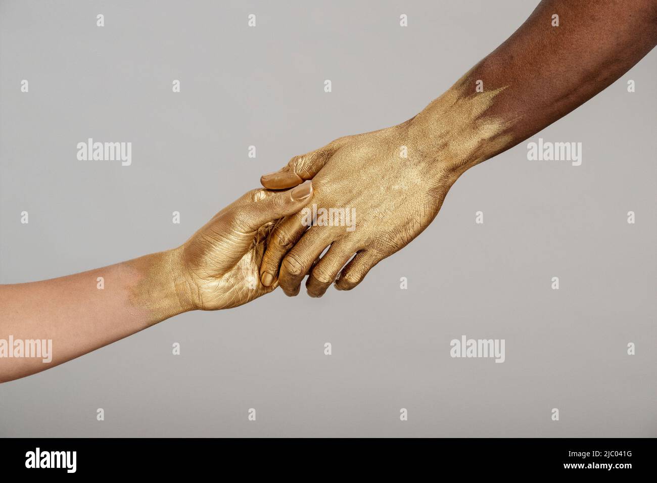Detailaufnahme einer Frau mit gemischter Rasse und eines schwarzen Mannes mit goldfarbenen Händen, die die Hände halten. Stockfoto
