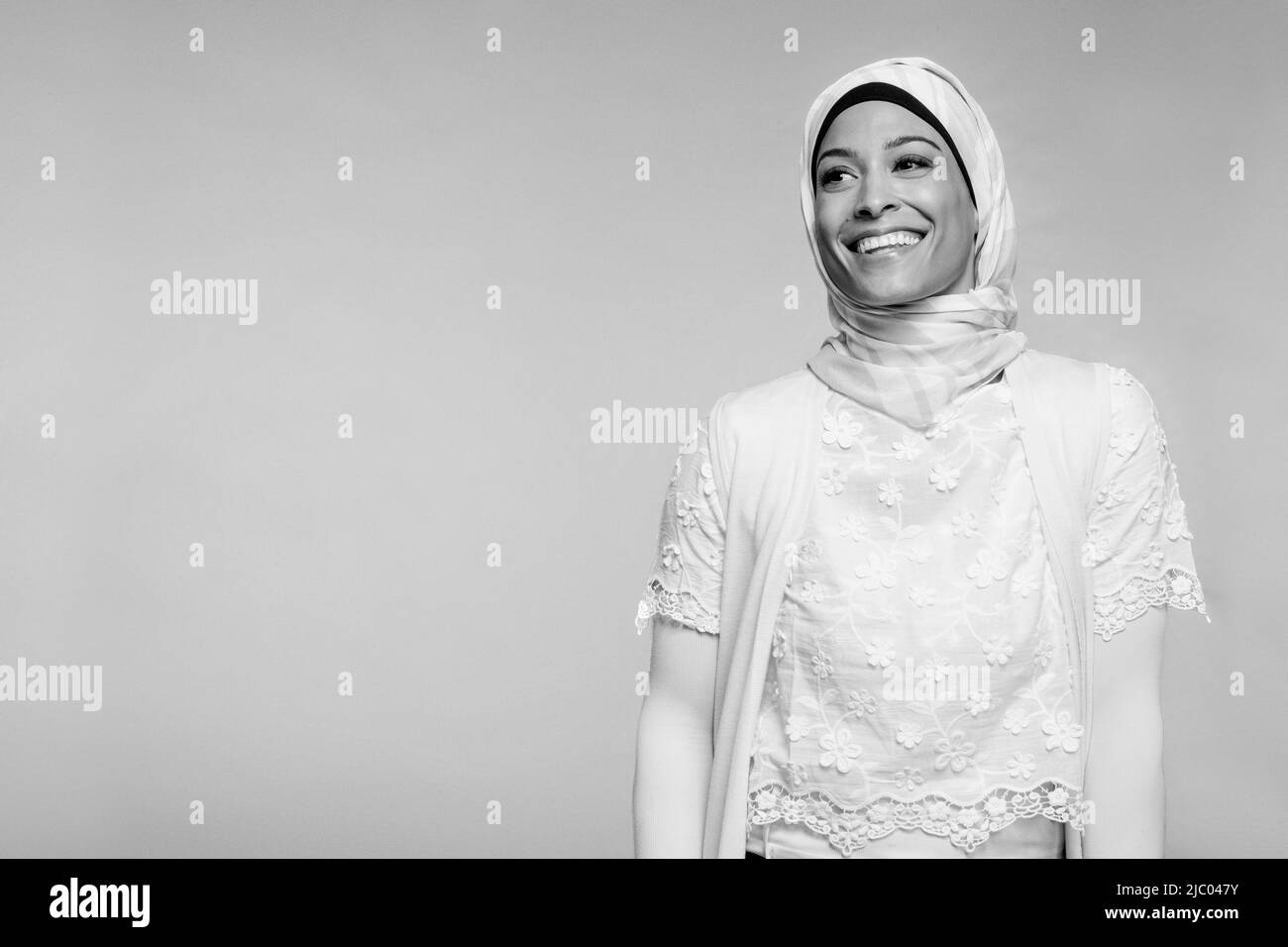 Entsättigte Porträt einer Frau mit gemischter Rasse auf grauem Hintergrund, die einen Hijab trägt. Stockfoto
