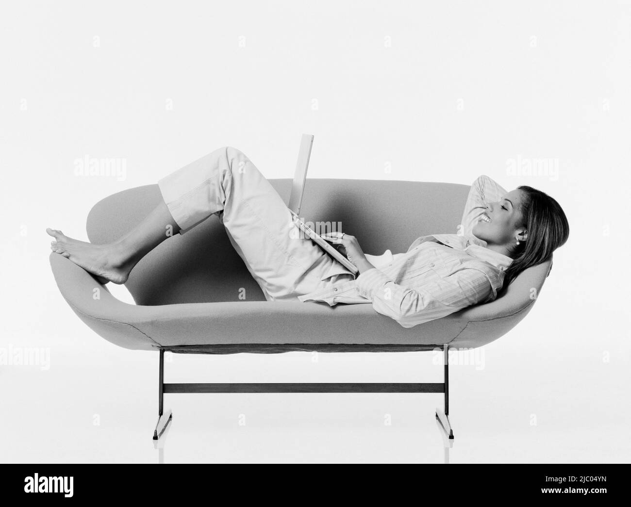 Junge Frau mit Laptop auf Couch entspannen Stockfoto