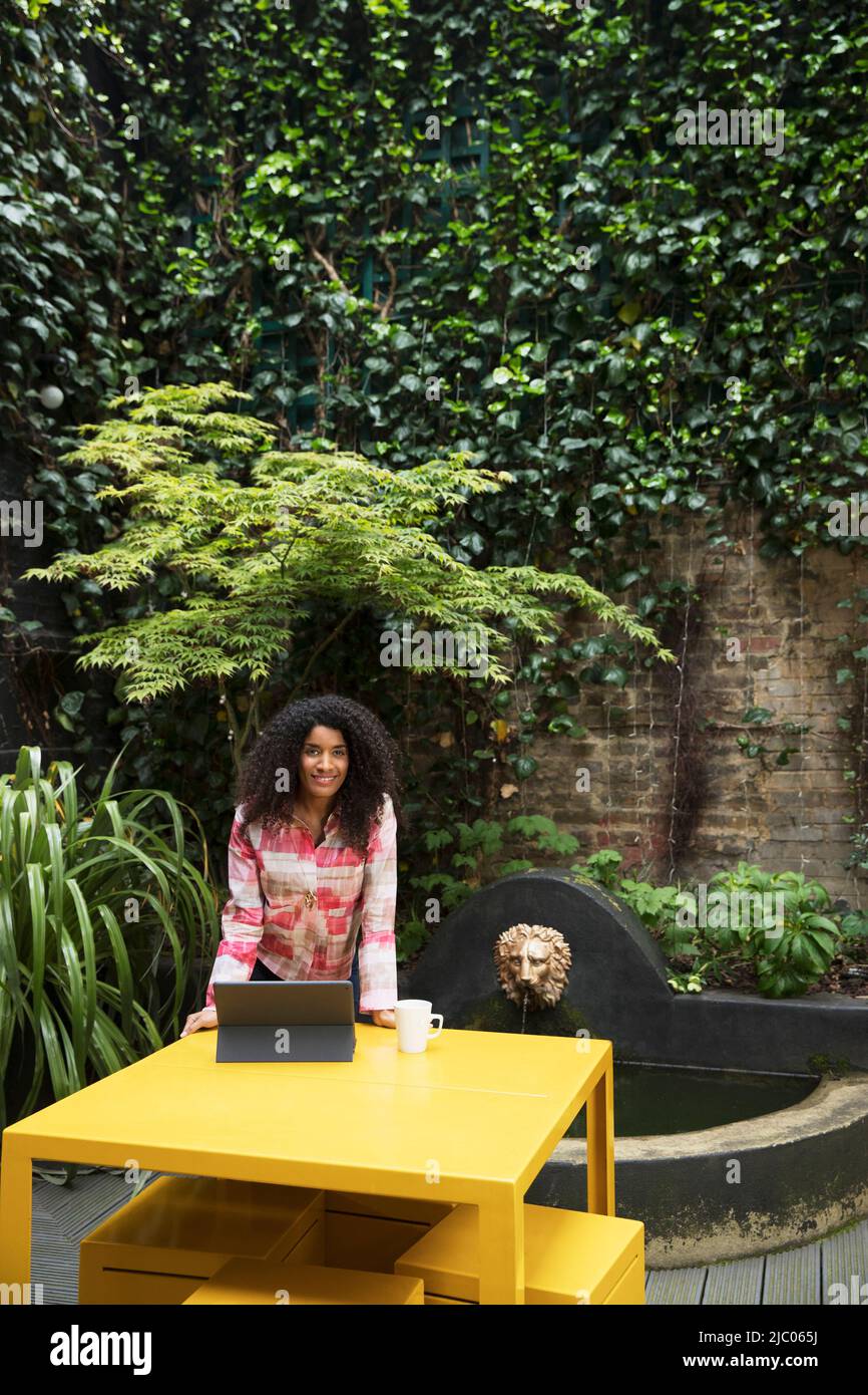 Frau, die am Tisch auf der Terrasse im Co-Working-Bereich am Tablet arbeitet Stockfoto