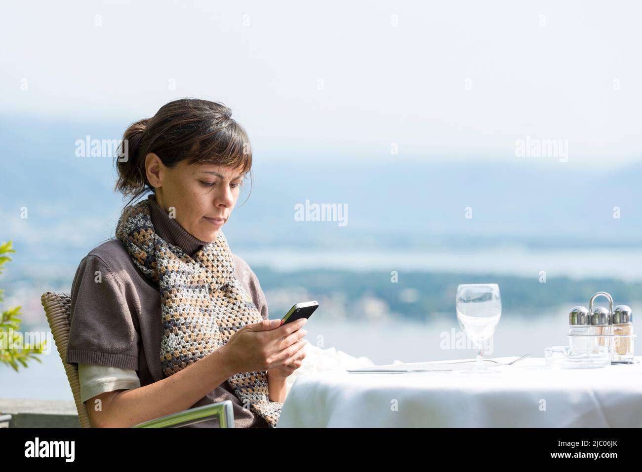Frau sitzt in einem Restaurant und benutzt ihr Telefon in der Schweiz. Stockfoto