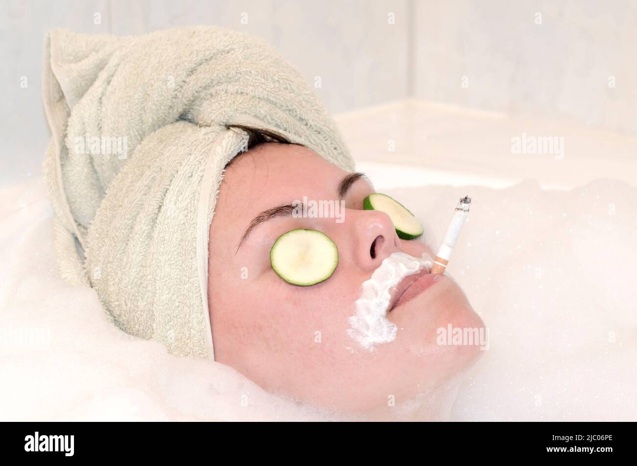Frau entspannen in Badewanne mit Gurke auf ihre Augen und Rauchen. Stockfoto